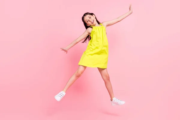 Foto de longitud completa de dulce brillante niña de la escuela usar vestido amarillo gafas oscuras saltando alto aislado color rosa fondo —  Fotos de Stock