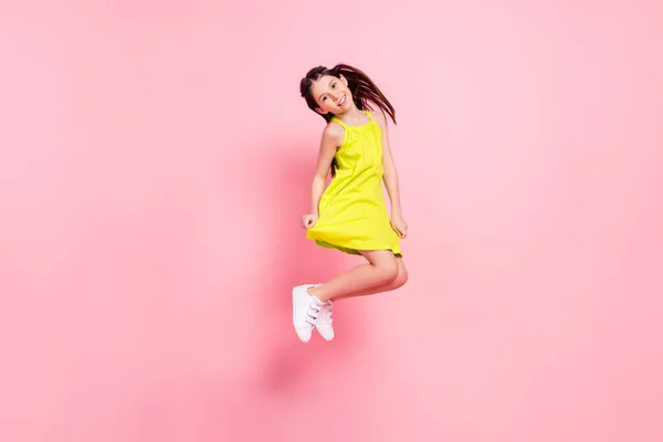 Фотографія повної довжини смішної чарівної школярки, одягненої в жовтий одяг темні окуляри, стрибають високо посміхненим ізольованим рожевим кольором фоном — стокове фото