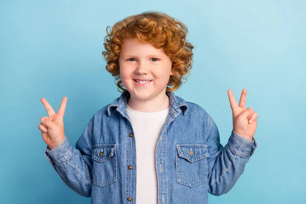 Photo de sympathique gai petit garçon foxy montrer v-signe symboles porter jeans veste isolé fond de couleur bleue — Photo