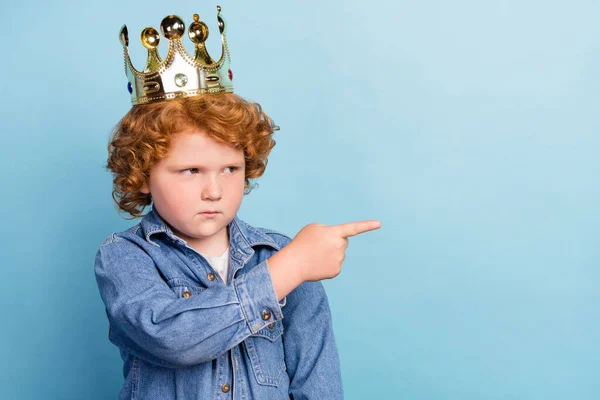 Foto portrét kudrnatý malý chlapec ukazující prst copyspace na sobě koruna izolované pastel modrá barva pozadí — Stock fotografie