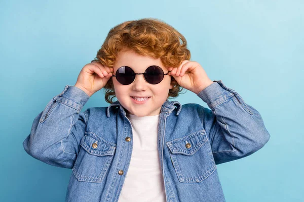 Foto retrato rizado niño sonriendo usando gafas de sol con estilo aislado pastel color azul fondo —  Fotos de Stock