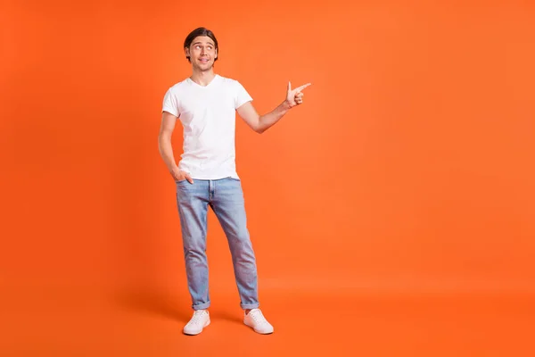 Full storlek foto av glad positiv glad man ser pekfingret tomt utrymme isolerad på orange färg bakgrund — Stockfoto