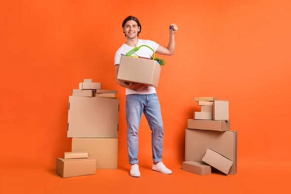 Foto in voller Länge junge glückliche positive Mann halten Hand Schlüssel bewegen Boxen isoliert auf orangefarbenem Hintergrund — Stockfoto