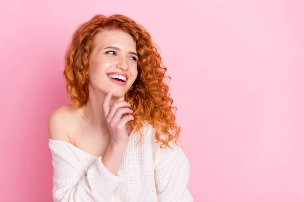 Foto retrato de la chica rizada sonriendo en suéter con fuera de hombro mirando copyspace tocando la barbilla aislado pastel de color rosa de fondo — Foto de Stock