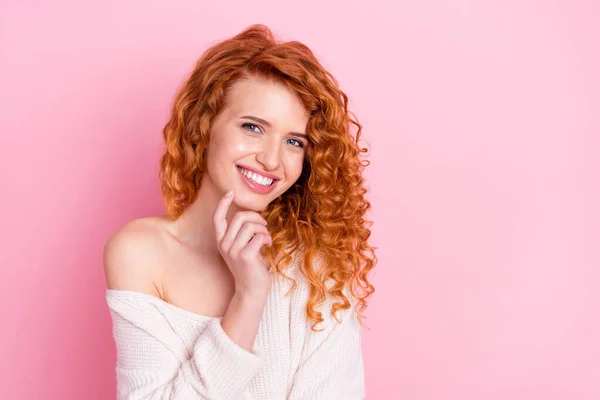Foto retrato de menina encaracolado sorrindo em suéter com off-ombro tocando queixo sonhador dente isolado pastel cor-de-rosa fundo — Fotografia de Stock