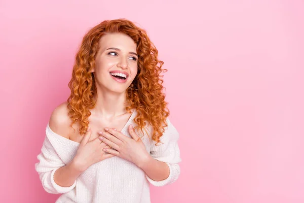 Foto retrato de chica rizada riendo feliz mirando vacío espacio manos en el pecho aislado pastel color rosa fondo — Foto de Stock