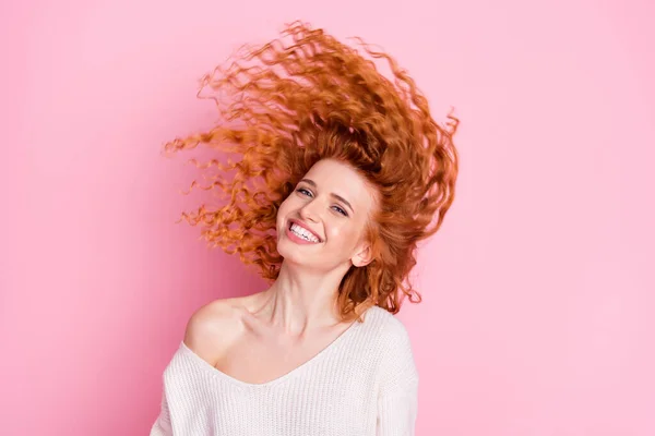 Портрет молодой девушки, улыбающейся волосам, летящим в воздухе в белом свитере с изолированным от плеча пастельно-розовым цветом фона — стоковое фото