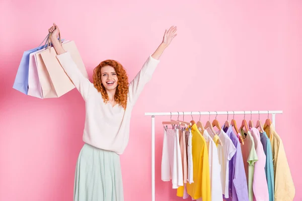 Zdjęcie młodej podekscytowanej dziewczyny szczęśliwy pozytywny uśmiech zakupoholiczka sklep ubrania wieszaki kolekcji izolowane na różowym tle koloru — Zdjęcie stockowe