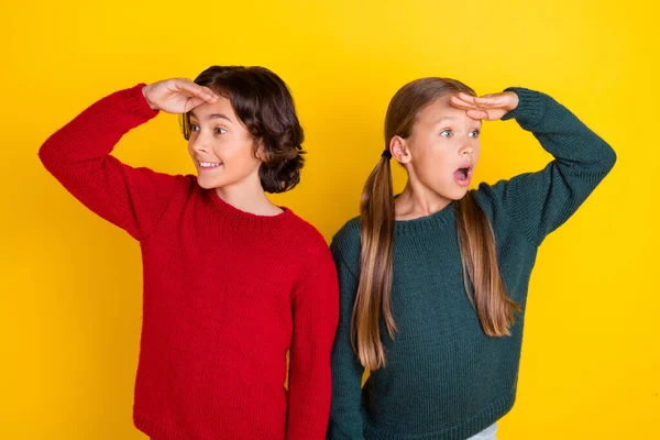Foto retrato dos niños asombrados mirando lejos manos cerca de la frente aislado color amarillo vivo fondo —  Fotos de Stock