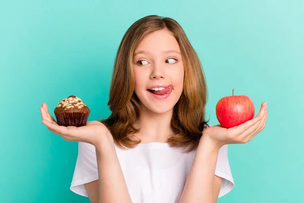 Foto retrato menina comparando doce cupcake maçã lambendo lábio fome isolado brilhante cor teal fundo — Fotografia de Stock