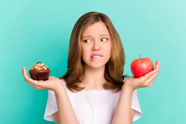 Foto retrato menina escalar doce cupcake maçã mordendo lábio incerto tem dúvida isolado brilhante cor teal fundo — Fotografia de Stock