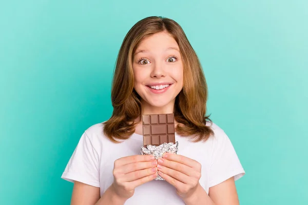 Foto retrato menina sorrindo feliz comer chocolate isolado vivo cor teal fundo — Fotografia de Stock