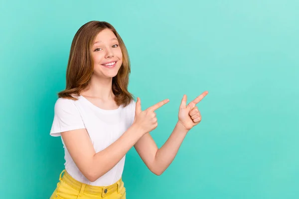 Foto retrato menina sorrindo apontando dedo mostrando copyspace isolado cor viva teal fundo — Fotografia de Stock