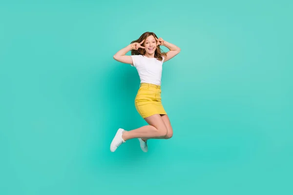 Teljes hossz testméret fotó iskoláslány ugrás fel mutatja v-jel gesztus túl boldog elszigetelt élénk színű háttér — Stock Fotó