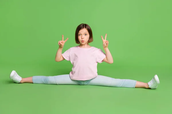 Full size foto van jong meisje zitten vloer flexibele sportieve show vrede koele v-teken pruillip geïsoleerd over groene kleur achtergrond — Stockfoto