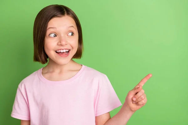 Foto di giovane bambina felice sorriso positivo punto dito vuoto spazio annuncio scelta selezionare isolato su sfondo di colore verde — Foto Stock