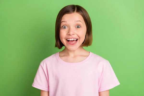 Foto von jungen aufgeregten Schulmädchen glücklich positives Lächeln erstaunt schockierte Nachrichten isoliert über grüne Farbe Hintergrund — Stockfoto