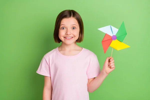 Foto de joven alegre chica feliz sonrisa positiva sostener papel molino de viento de juguete aislado sobre fondo de color verde — Foto de Stock