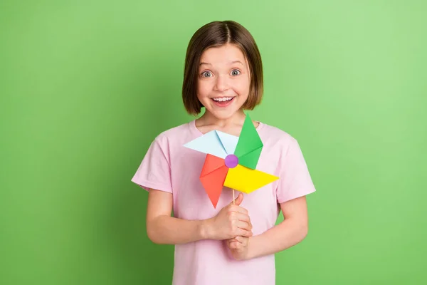 Foto von jungen fröhlichen kleinen Mädchen glücklich positives Lächeln spielen Windmühle Kindheit isoliert über grüne Farbe Hintergrund — Stockfoto