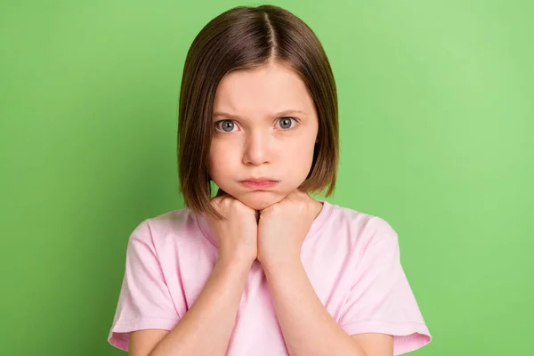 Photo of young little girl unhappy sad upset hand touch chin bored offended isolated over green color background Royalty Free Stock Images