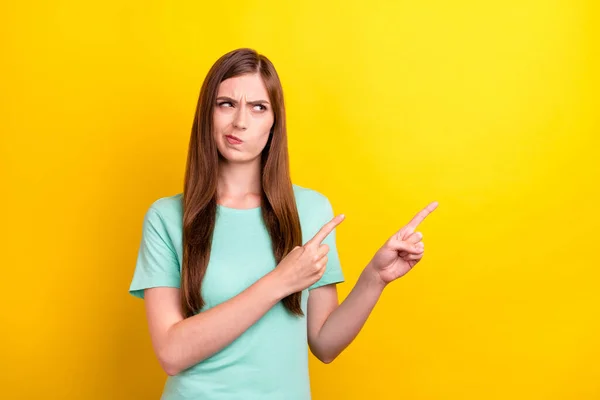 Foto van onzeker brunette kapsel duizendjarige dame punt kijken lege ruimte dragen teal t-shirt geïsoleerd op gele kleur achtergrond — Stockfoto