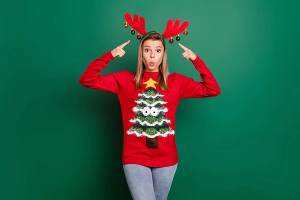 Porträt der attraktiven verblüfft funky Mädchen trägt hässlichen Pullover demonstriert Hörner Dezember Tradition isoliert über grünen Farbhintergrund — Stockfoto