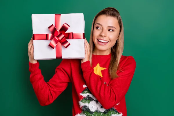 Portrét atraktivní zvědavé veselá dívka drží v ruce dárkové krabice Vánoce izolované přes zelenou barvu pozadí — Stock fotografie