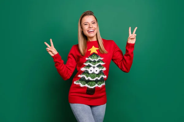 Портрет привабливої веселої щасливої дівчини, що показує v-знак весело Різдвяний час ізольовано на зеленому кольоровому фоні — стокове фото