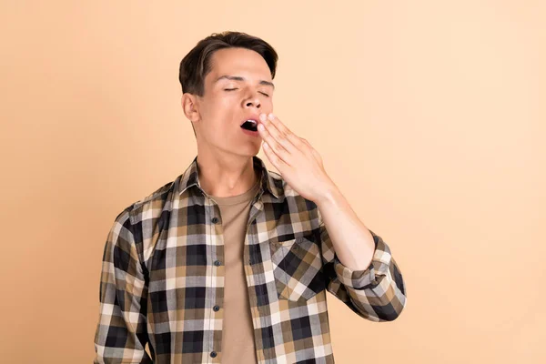 Photo of tired exhausted guy palm cover open mouth yawn wear checkered shirt isolated beige color background — Stock Photo, Image