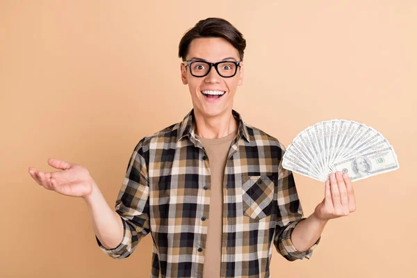 Foto de cara animado engraçado segurar fã dinheiro nota desgaste xadrez camisa isolado bege cor fundo — Fotografia de Stock