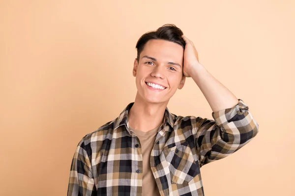 Foto van millennial mooie kerel hand hoofd slijtage geruite shirt geïsoleerd op beige kleur achtergrond — Stockfoto