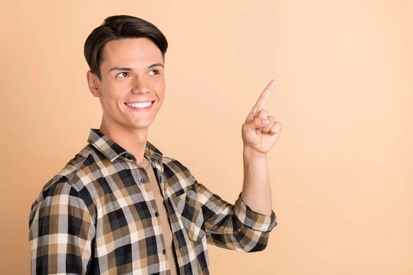 Photo of young cute guy point empty space wear checkered shirt isolated on beige color background — Stock Photo, Image