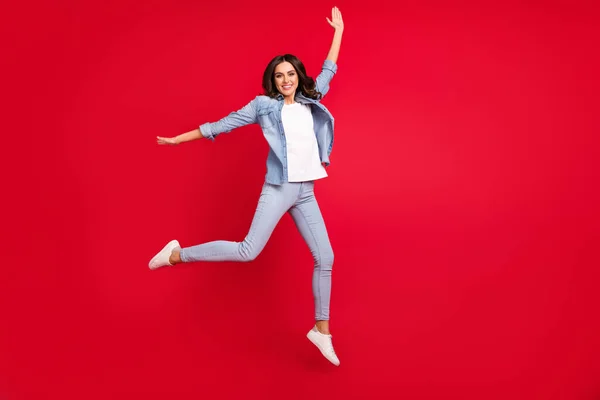Lunghezza completa dimensione del corpo vista di attraente spensierata ragazza allegra salto a piedi divertendosi isolato su vibrante sfondo di colore rosso — Foto Stock