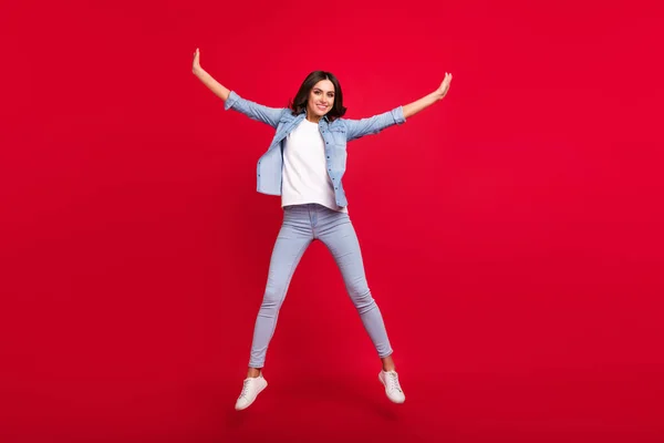 Full length body size view of attractive carefree cheerful girl jumping having fun isolated over vibrant red color background — Stock Photo, Image