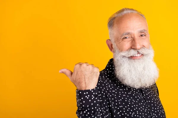 Foto av glad glad glad gammal man peka finger tumme tomt utrymme gott humör försäljning isolerad på gul färg bakgrund — Stockfoto