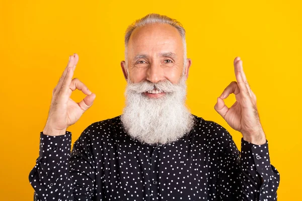 Foto de atractivo alegre viejo abuelo sonrisa mostrar manos bien canta promo aislado sobre fondo de color amarillo —  Fotos de Stock