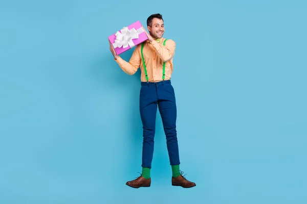 Foto pria tampan melompat terus hadir kotak memakai suspender kemeja terisolasi biru latar belakang warna — Stok Foto
