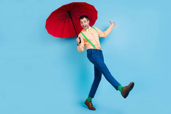 Full body foto van gaan brunet man met parasol slijtage shirt broek sokken schoenen geïsoleerd op blauwe kleur achtergrond — Stockfoto