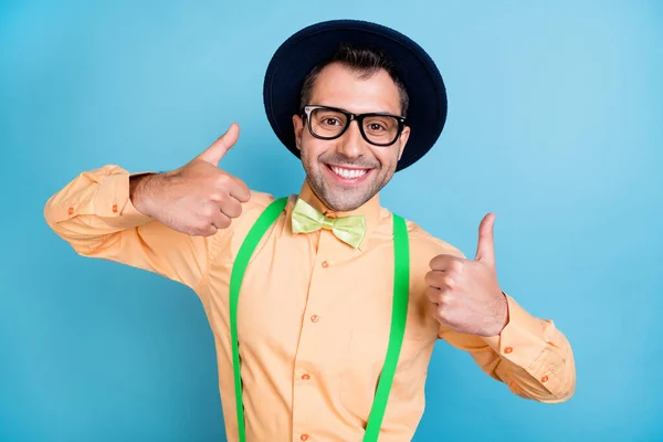 Foto de brunet fresco hombre pulgar hacia arriba desgaste gorra gafas de la camisa del melocotón gafas aisladas sobre fondo de color azul —  Fotos de Stock