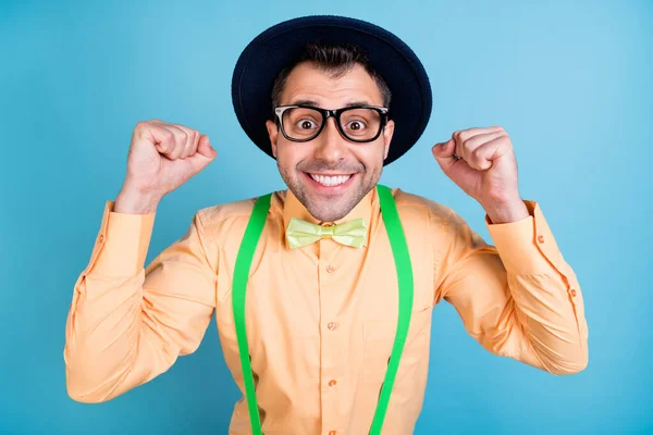 Foto de hooray morena hombre manos puños desgaste gorra gafas camisa melocotón gafas aisladas sobre fondo de color azul —  Fotos de Stock