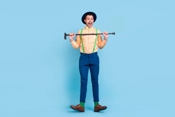 Foto van gekke danser man houden riet dans open mond dragen hoed bretels shirt strik geïsoleerde blauwe kleur achtergrond — Stockfoto