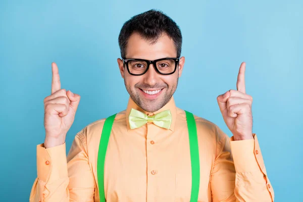 Foto van slimme brunet jonge man punt lege ruimte dragen perzik shirt bril geïsoleerd op blauwe kleur achtergrond — Stockfoto
