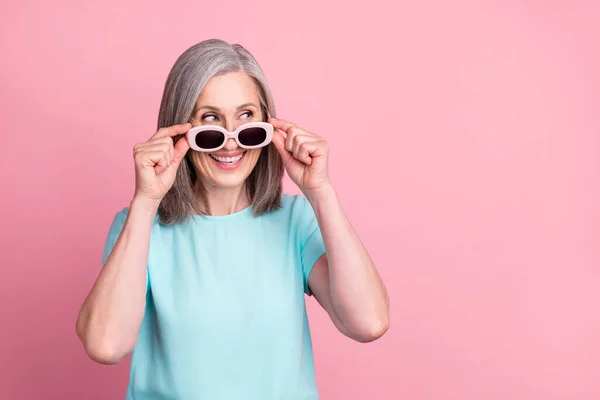 Foto av funky åldern vitt hår dam ser tomt utrymme slitage glasögon teal blus isolerad på rosa färg bakgrund — Stockfoto