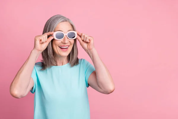 Fénykép az impresszált öreg fehér haj hölgy néz üres tér kopás szemüveg teal blúz elszigetelt rózsaszín szín háttér — Stock Fotó