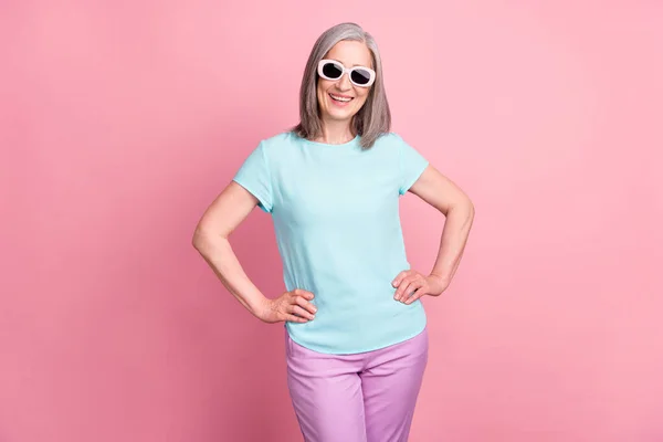 Foto de engraçado velho cabelo branco senhora desgaste óculos teal blusa calças isoladas no fundo cor-de-rosa — Fotografia de Stock