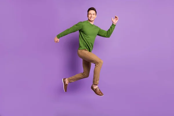 Full längd profil foto av ung brunett kille hoppa bära tröja byxor sneakers isolerad på lila bakgrund — Stockfoto