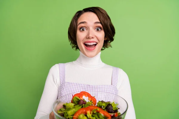 Фотопортрет жінки, що тримає овочевий салат здивований ізольованим пастельним зеленим кольором фону — стокове фото