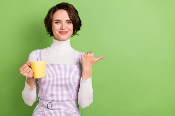 Foto retrato mulher mantendo xícara de café apontando polegar copyspace isolado pastel cor verde fundo — Fotografia de Stock