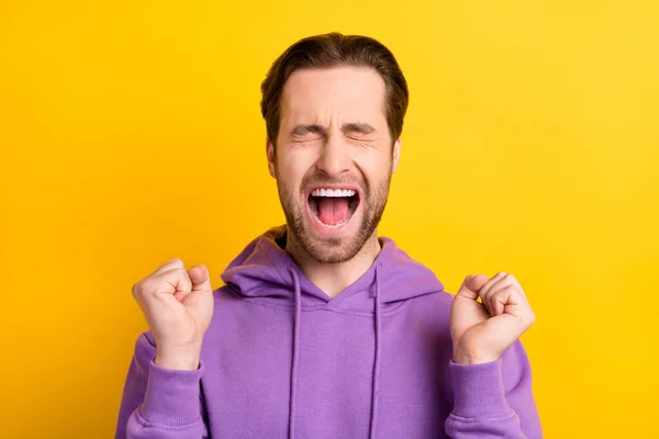 Фото чемпиона триумфальный парень кричать поднять кулаки закрыв глаза носить фиолетовый свитер изолированы желтый цвет фона — стоковое фото