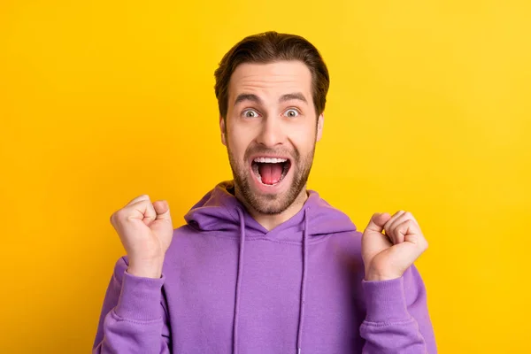 Foto de loco ganador chico boca abierta levantar puños gritar sí usar sudadera violeta aislado color amarillo fondo —  Fotos de Stock